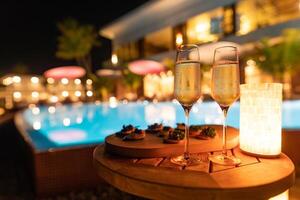 romantisches dekor bei kerzenlicht tisch für party mit champagner-spezialgerichten und verschwommenem licht von pool und haus. Luxusparty oder Urlaubsveranstaltung foto