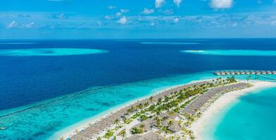 luftaufnahme der malediveninsel, des luxuriösen wasservillenresorts und des holzstegs. schöner himmel und ozeanlagune strandhintergrund. Sommerferien Urlaub und Reisekonzept. paradies luftlandschaft pano foto