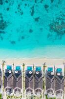 Luxus Strand Villen, tolle Blau Meer mit Haus Riff Korallen Über Weiß sandig Strand. perfekt Sommer- Tourismus Ferien oder Urlaub Konzept im Malediven oder Französisch Polynesien Reise foto