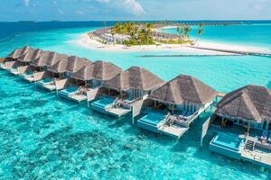 luftaufnahme der malediveninsel, des luxuriösen wasservillenresorts und des holzstegs. schöner himmel und ozeanlagune strandhintergrund. Sommerferien Urlaub und Reisekonzept. paradies luftlandschaft pano foto