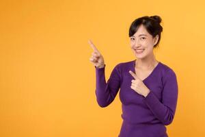 schön jung asiatisch Frau 30er Jahre tragen lila Hemd zeigen oben zu Kopieren Raum mit Lächeln Gesicht und glücklich. ziemlich Mädchen Handlung mögen ein zufrieden Produkt, verwenden zum Werbung mit Gelb Hintergrund foto