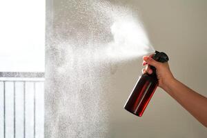 ein Frau Hand Sprays ein Luft Erfrischer im ein Zimmer. foto