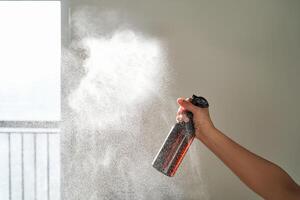 ein Frau Hand Sprays ein Luft Erfrischer im ein Zimmer. foto