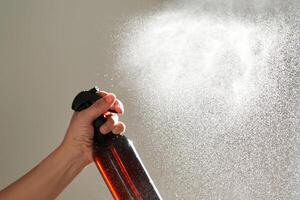 ein Frau Hand Sprays ein Luft Erfrischer im ein Zimmer. foto