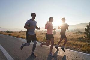 ein Gruppe von Freunde, Sportler, und Jogger Umarmung das früh Morgen Std wie Sie Lauf durch das neblig Dämmerung, erregt durch das steigend Sonne und umgeben durch das still Schönheit von Natur foto