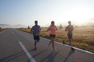 ein Gruppe von Freunde, Sportler, und Jogger Umarmung das früh Morgen Std wie Sie Lauf durch das neblig Dämmerung, erregt durch das steigend Sonne und umgeben durch das still Schönheit von Natur foto