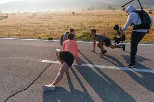 hinter das Linse. Videograf erfasst Sportler Erwärmen oben zum Morgen laufen. foto