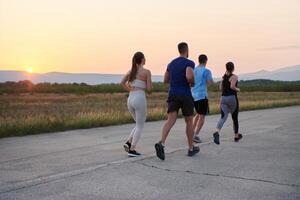 ein vielfältig Gruppe von Läufer Züge zusammen beim Sonnenuntergang. foto