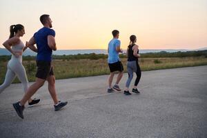 ein vielfältig Gruppe von Läufer Züge zusammen beim Sonnenuntergang. foto