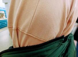 zurück Aussicht von ein Frau tragen ein Grün Jacke mit ein Reißverschluss. foto