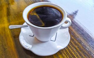 Weiß Tasse von schwarz Americano Kaffee auf ein hölzern Tisch. foto
