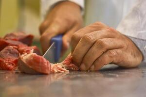 Metzger reinigt das Fleisch von Verunreinigungen foto