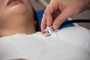 Arzt Hand halten Stethoskop zum Überprüfung Herzschlag von krank weiblich geduldig beim Krankenhaus. Gesundheit Untersuchung Konzept foto