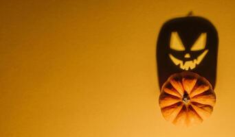 Halloween Hintergrund Konzept. Jack Ö Kürbis wütend Gesicht Schatten. gespenstisch lächelnd Schatten von ein Orange Kürbis Laterne oben Aussicht schließen hoch, Halloween Party Design foto