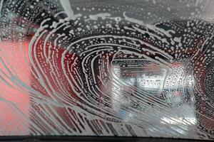 Auto Fenster mit Weiß Seife Schaum während Waschen Wagen. foto