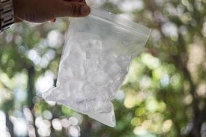 Hand halten Eis Würfel im transparent Plastik Taschen foto