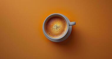 oben Aussicht von ein Tasse von Kaffee mit Zimt Sträusel auf ein Orange Hintergrund foto