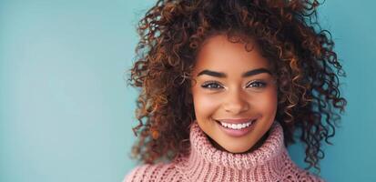 Frau mit lockig Haar lächelnd im Rosa Sweatshirt gegen Blau Hintergrund foto