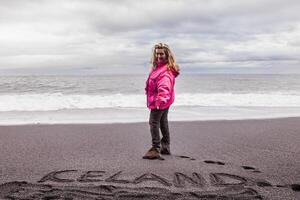 schön blond Tourist auf das schwarz Strand von vik foto