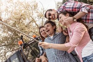 glücklich Gruppe von tausendjährig Menschen nimmt ein Selfie draussen Sitzung im ein Auto foto