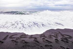 handgeschrieben Inschrift auf schwarz Sand von vik foto