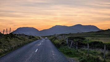 Auto Fahren auf leeren szenisch Straße Trog Natur und Berge beim Sonnenuntergang, connemara National Park, Bezirk Galway, Irland foto