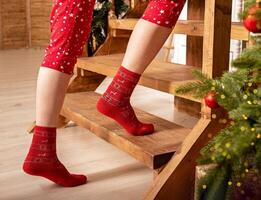 Weihnachten Socken im Winter heim. warm Füße von Frau mit rot gemütlich Weihnachten Socken. Hitze heiß wolle Komfort foto