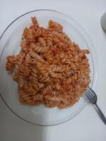 Fusilli Pasta mit Tomate Soße auf ein Weiß Teller mit ein Gabel foto