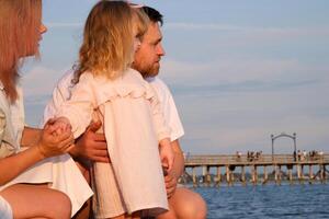 jung Familie Mutter Vater und Tochter auf das Strand suchen beim das Meer foto