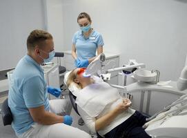 Dental Klinik Zähne Bleaching Frau Lügen unter Gerät Arzt und Krankenschwester Frau Hände halten Panik Taste darüber hinaus polus Plus fortgeschritten Bleaching System mit Dental uv Laser- Bleaching Gerät foto