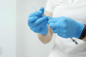 weiblich Hände im Blau hygienisch Handschuhe Nahansicht mit ein Spritze im Hände zum Anästhesie tun ein Injektion von ein Krankheit genesen Behandlung Krankenhaus Zahnarzt Zahnheilkunde Krankenhaus covid foto