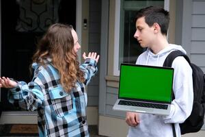 Jugendliche im Hände mit ein Laptop und ein Rucksack Grün Bildschirm Chromakey Mädchen überrascht Verbreitung ihr Waffen zu das Seiten Junge sieht aus beim aussehen beim jeder andere freunde Klassenkameraden Werbung Schock Raum zum Text foto