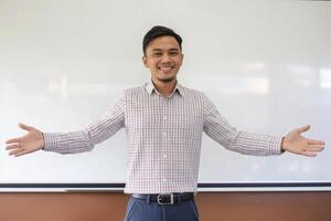 ein lächelnd malaiisch männlich Lehrer Begrüßung Schüler im Klassenzimmer foto