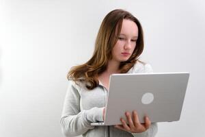 Bild von ein jung blond Frau Sitzung auf ein Weiß Oberfläche mit ein Laptop im ihr Schoß. foto