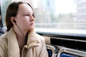 jung Mädchen Teenager Fahrten im Transport sieht aus aus das Fenster blinkt Häuser Nahansicht Ruhe friedlich Gesicht Raum zum Text Himmel Zug Bus Auto gewöhnliche Person im echt Leben Straße Städte Vancouver Vorort foto