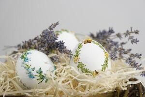 Stickerei mit Bänder auf Eierschalen Ostern Urlaub Muster Stickerei Bänder auf Eierschale Lavendel Blumen Dekoration Nahansicht Ostern Urlaub gelungen Rasuren zum Verpackung auf ein Blau Hintergrund foto