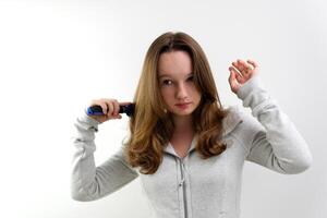 Kämmen Haar mit ein Blau Kamm auf ein Weiß Hintergrund schön gepflegt gesund Haar von ein Teenager Mädchen Jugend jung Körper Ausgezeichnet Shampoos Masken Balsame Schönheit Kugel persönlich Pflege foto