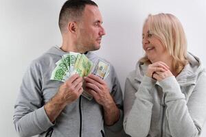 ein mittleren Alters Ehefrau fragt ihr Mann zum Geld zu Kaufen Dollar und Euro, das Mann nimmt ein Teil von Es, das Ehefrau zählt Geld, viele anders Emotionen, Gespräche, ein Kuss foto