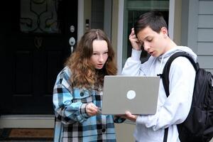 schwierig Aufgabe ein Junge und Mädchen Stehen auf das Veranda mit Laptop im Hände Überraschung Netzwerke interessant Botschaft Lernen online Neu Aufgabe zu lösen Problem Sein spät zum Kurs Jugendliche Jugend foto
