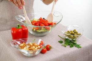 Nahansicht von Salat kneten mit hölzern Löffel Kirsche Tomaten Cocktail Gurken Oliven Beige Schürze und Weiß Hintergrund Raum zum Text Restaurant Essen Portion Tabelle Rahmen Mittagessen Abendessen Frühstück foto