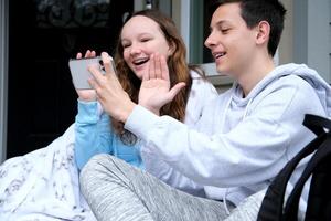 Bruder und Schwester kommunizieren online Welle Hallo Lachen Lächeln Freude von Kommunikation sitzen auf Veranda im Decke haben Spaß gehen auf Ferien entspannen im ein Sanatorium Jugend verlassen das Krieg im Ukraine foto