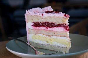 Essen Käsekuchen mit ein Gabel. nehmen beißen von Käsekuchen. Süss Dessert Essen schließen oben von ein Rosa Erdbeere Kuchen wirbelnd auf ein Weiß Platte. foto