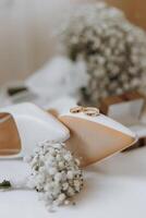 ein Paar von Weiß Schuhe mit Gold Ringe auf Sie sind auf ein Tabelle mit ein Strauß foto