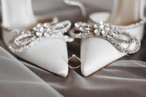 ein Paar von Weiß Schuhe mit ein Diamant Ring auf das links Schuh foto