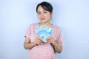Porträt von ein jung asiatisch Frau halten Kasse Geld Rechnungen lächelnd auf Weiß Hintergrund foto