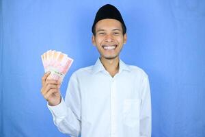 glücklich Ausdruck von asiatisch Muslim Mann halten Geld Rupiah Banknoten isoliert auf Weiß Hintergrund foto