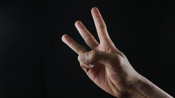 männlich Hand Geste Nummer drei Nahansicht isoliert auf ein schwarz Hintergrund foto