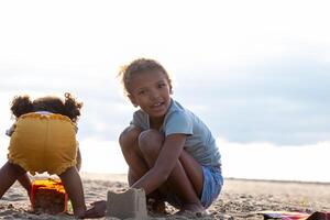 zwei Schwestern, Kinder engagieren im sandig Konstruktion auf ein Strand, ihr Freude und Zusammenarbeit offensichtlich im das Strand spielen, National Geschwister Tag und Zusammenarbeit. foto