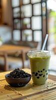 Tasse von Grün Tee Matcha Milch Eis trinken ist platziert auf das Bambus Matte foto