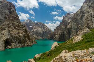 eingebettet beim das China Grenze, das makellos kel-su See offenbart Türkis Wasser umgeben durch robust Berge, Grün Vegetation schmücken das Landschaft, wolkig Himmel, hervorrufen heiter, natürlich Schönheit foto